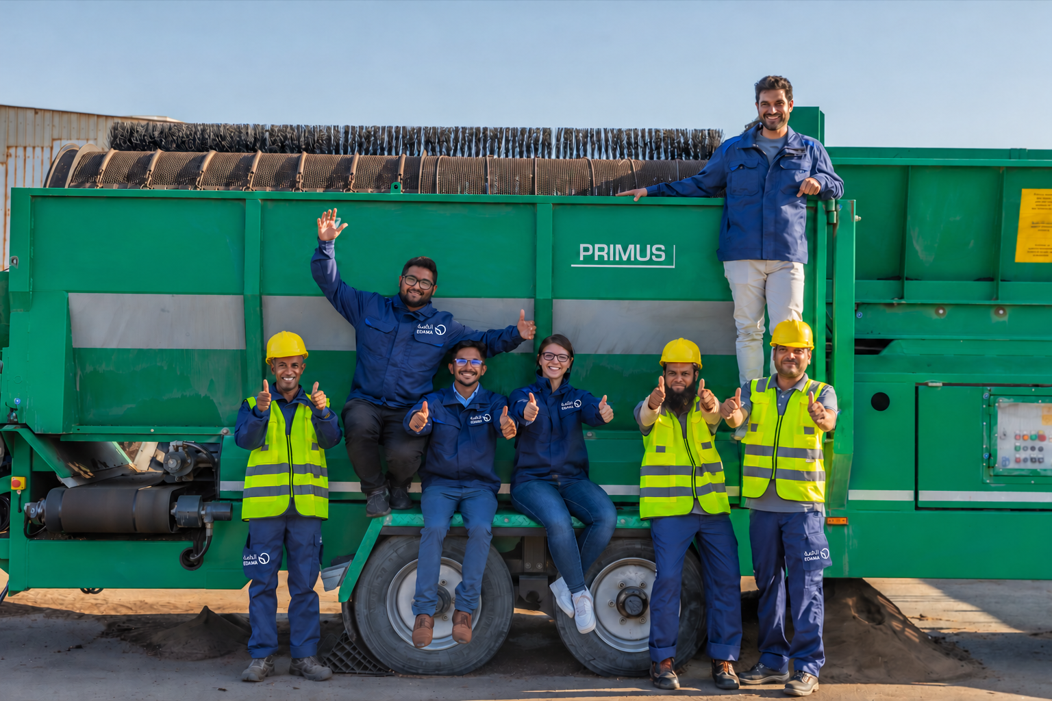 Edama operations team giving thumbs up, seated on and standing beside the green compost screener